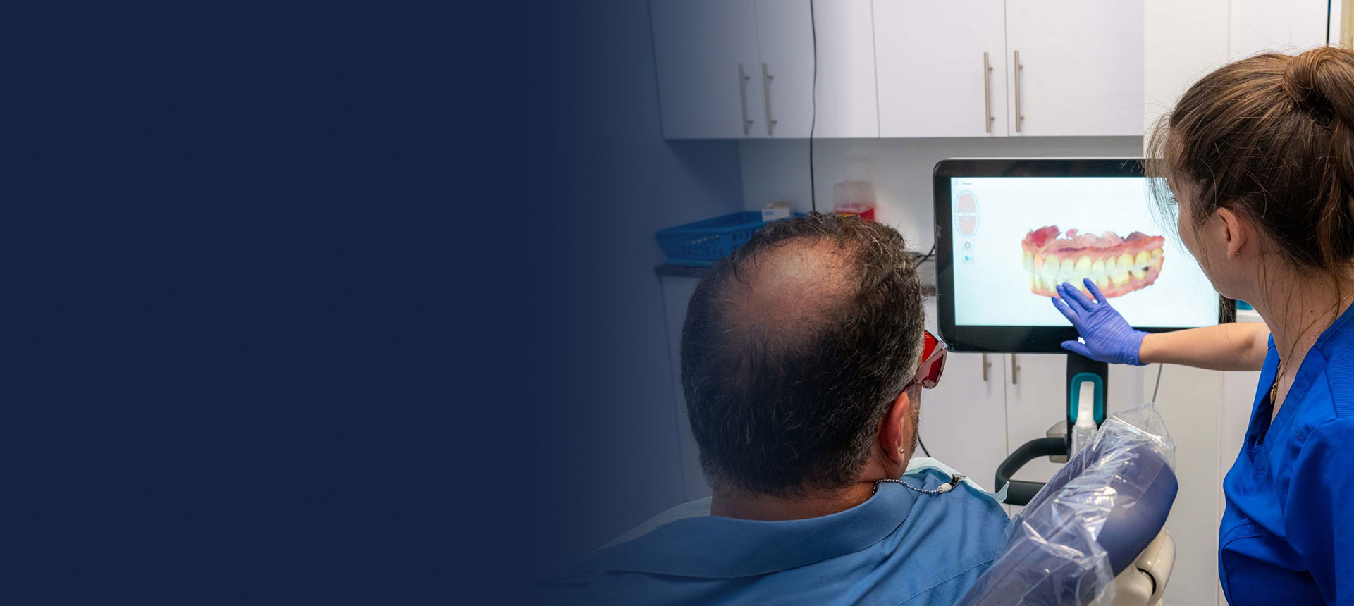 Dentist and assistant reviewing a digital scan during a dental implant consultation